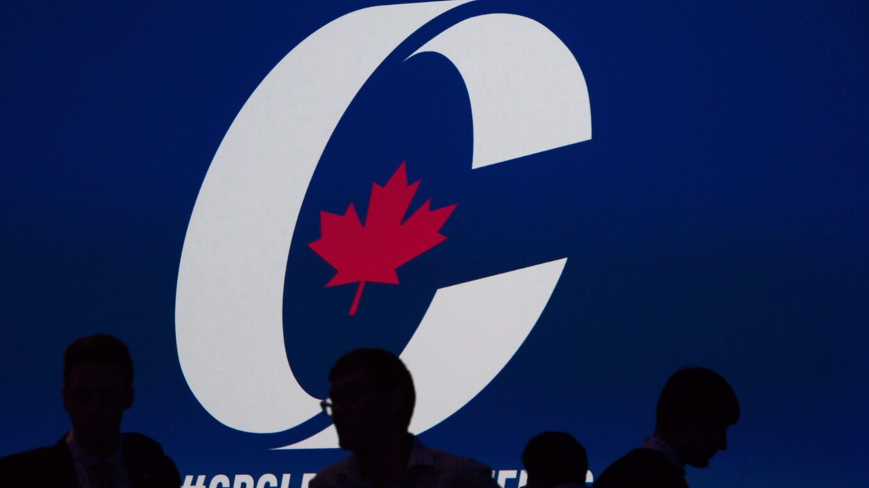 Le logo du Parti conservateur en arrière-plan avec des ombres de quatre personnes au devant