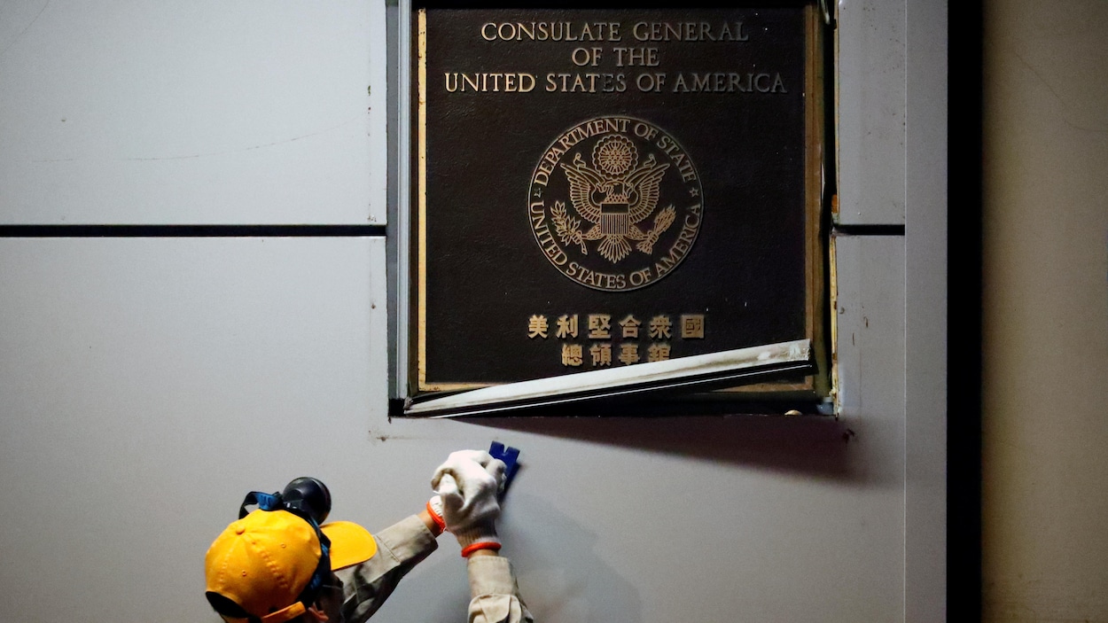 Un ouvrier retire une plaque des États-Unis sur l'édifice.