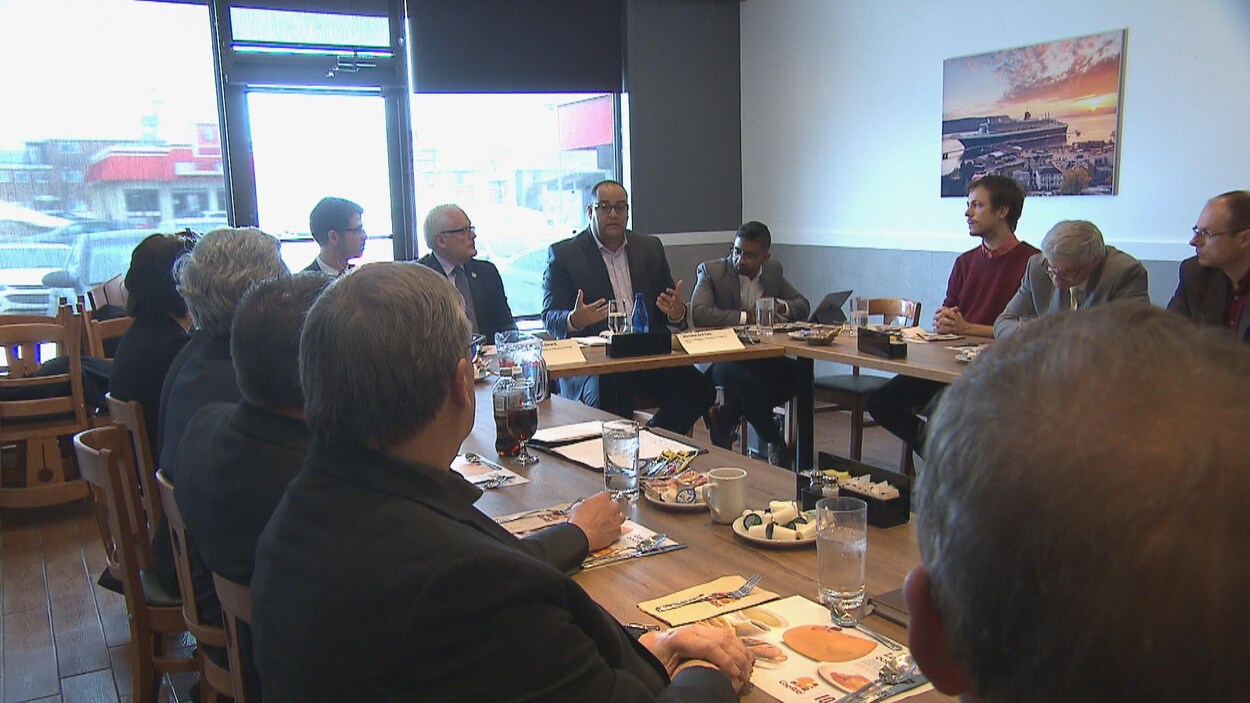 L'adjoint parlementaire du ministre des Finances, Saul Polo, est assis dans un restaurant entouré d'autres hommes. L'adjoint parlementaire du ministre des Finances, Saul Polo, est assis dans un restaurant entouré d'autres hommes.