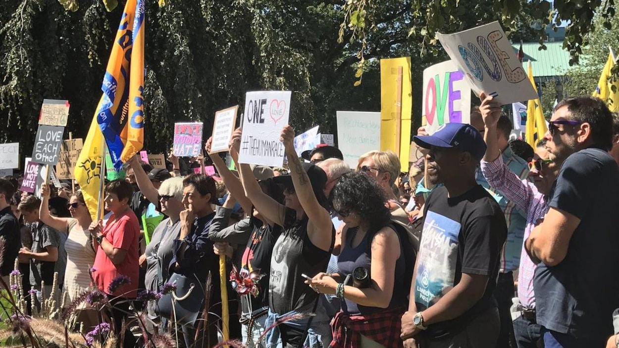 Des contre-manifestants tiennents des pancartes à l'hôtel de ville de Vancouver