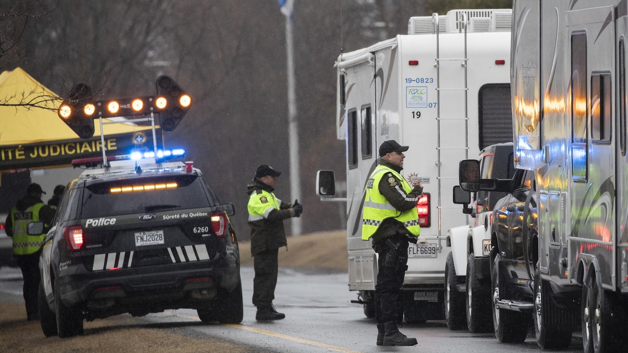 Des policiers interceptent des véhicules sur la route.