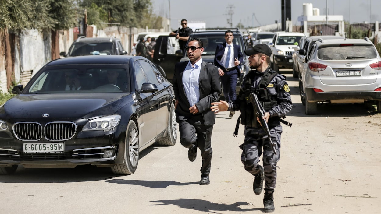 Un garde du corps de M. Hamdallah, en civil, et un membre des forces de sécurité du Hamas, en uniforme militaire, courent aux côtés du convoi transportant M. Hamdallah. Un garde du corps de M. Hamdallah, en civil, et un membre des forces de sécurité du Hamas, en uniforme militaire, courent aux côtés du convoi transportant M. Hamdallah.
