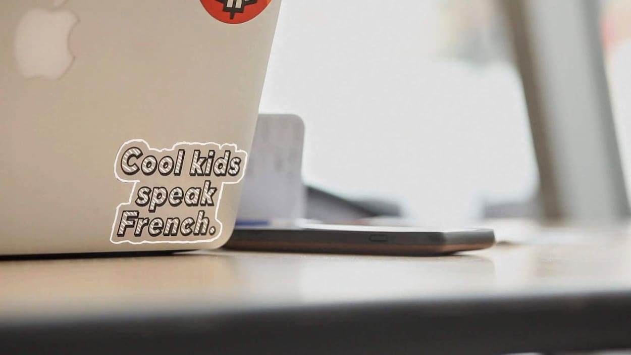 « Cool kids speak French » est écrit au dos d'un ordinateur.