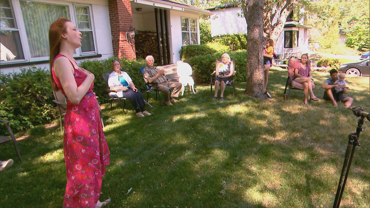 Une chanteuse offre un concert dehors chez des particuliers.