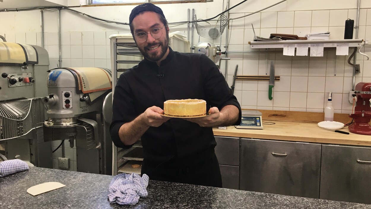 Corentin est en cuisine et tient dans ses mains un flan qu'il a préparé.