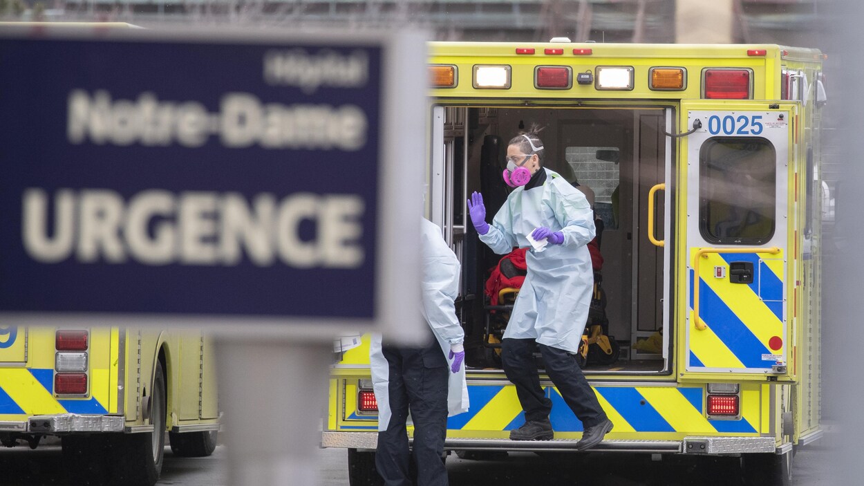 Une femme portant un masque sort d'une ambulance.
