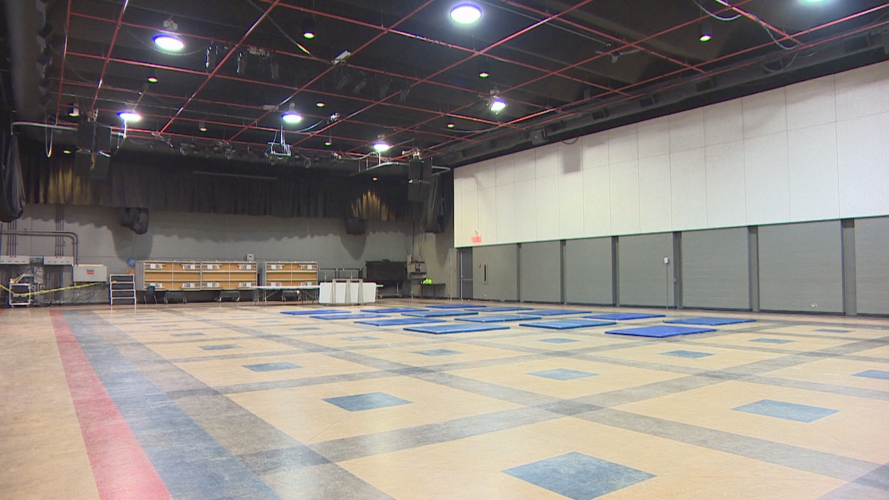 Une grande salle avec des matelas sur le sol.