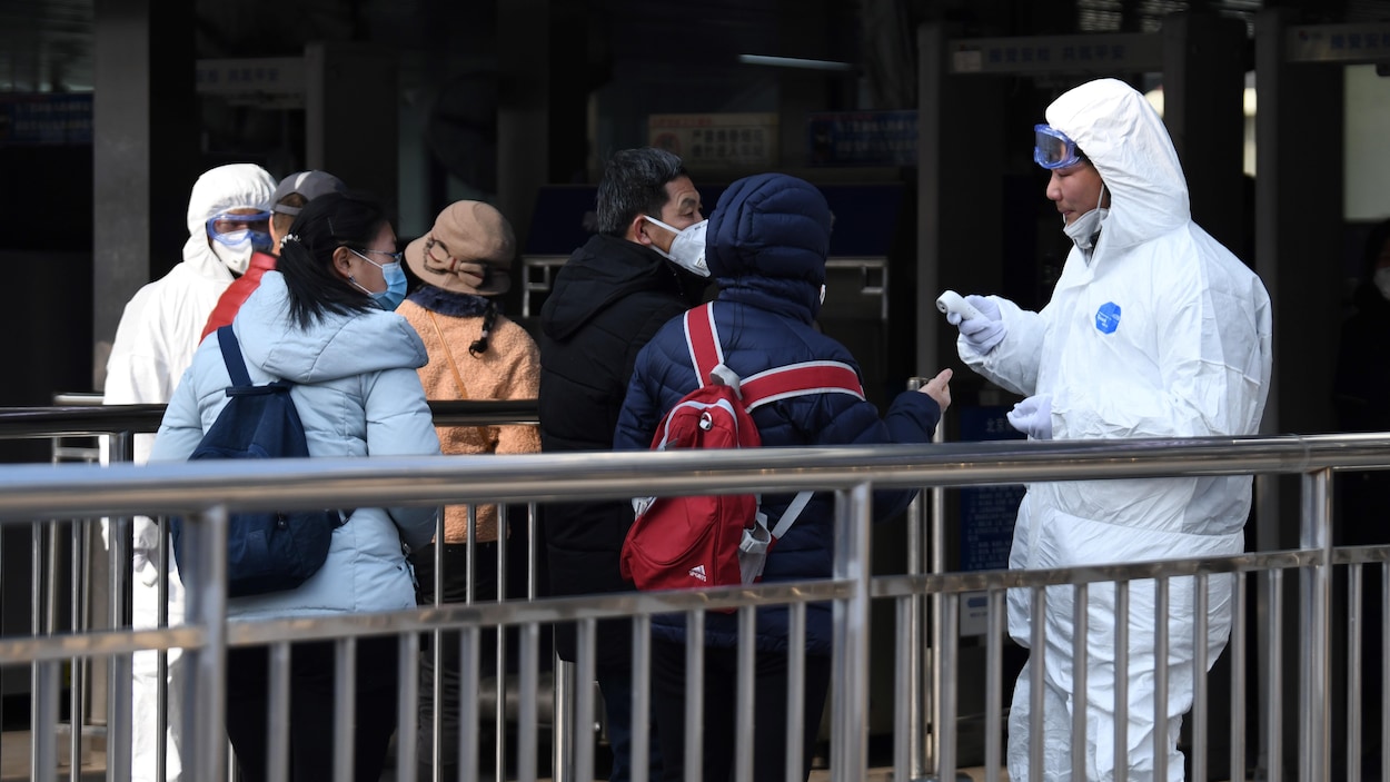 Les employés portant de l'équipement de protection abordent des passagers avec des masques.