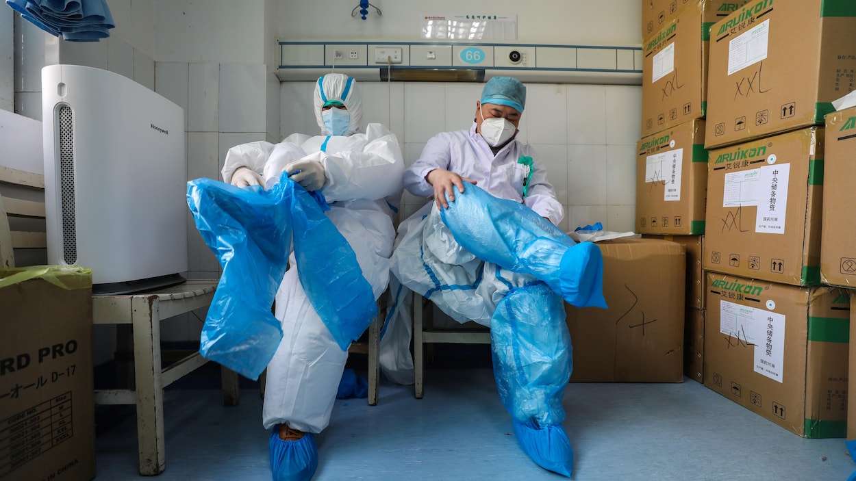Du personnel médical se prépare en enfilant des pantalons de protection.