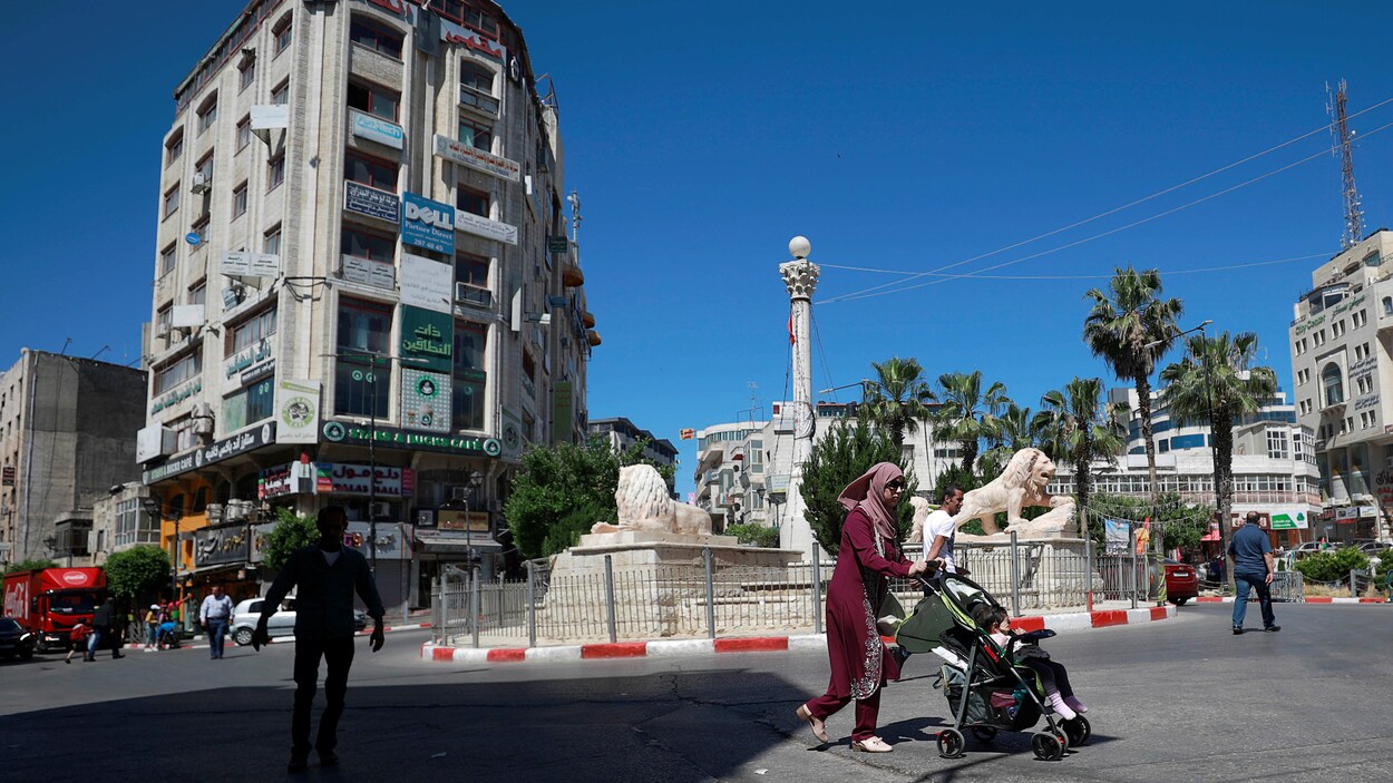 Une femme avec une poussette et des hommes marchant dans une rue.
