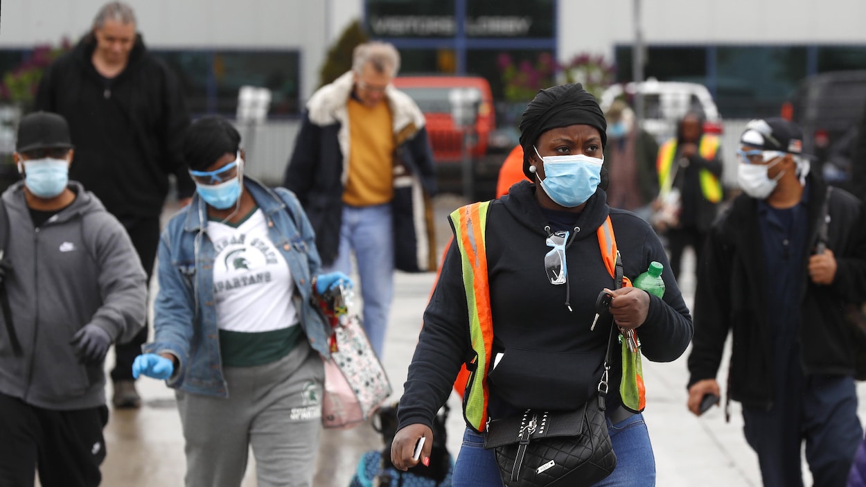 Des gens portant des masques marchent en s'éloignant de l'usine.