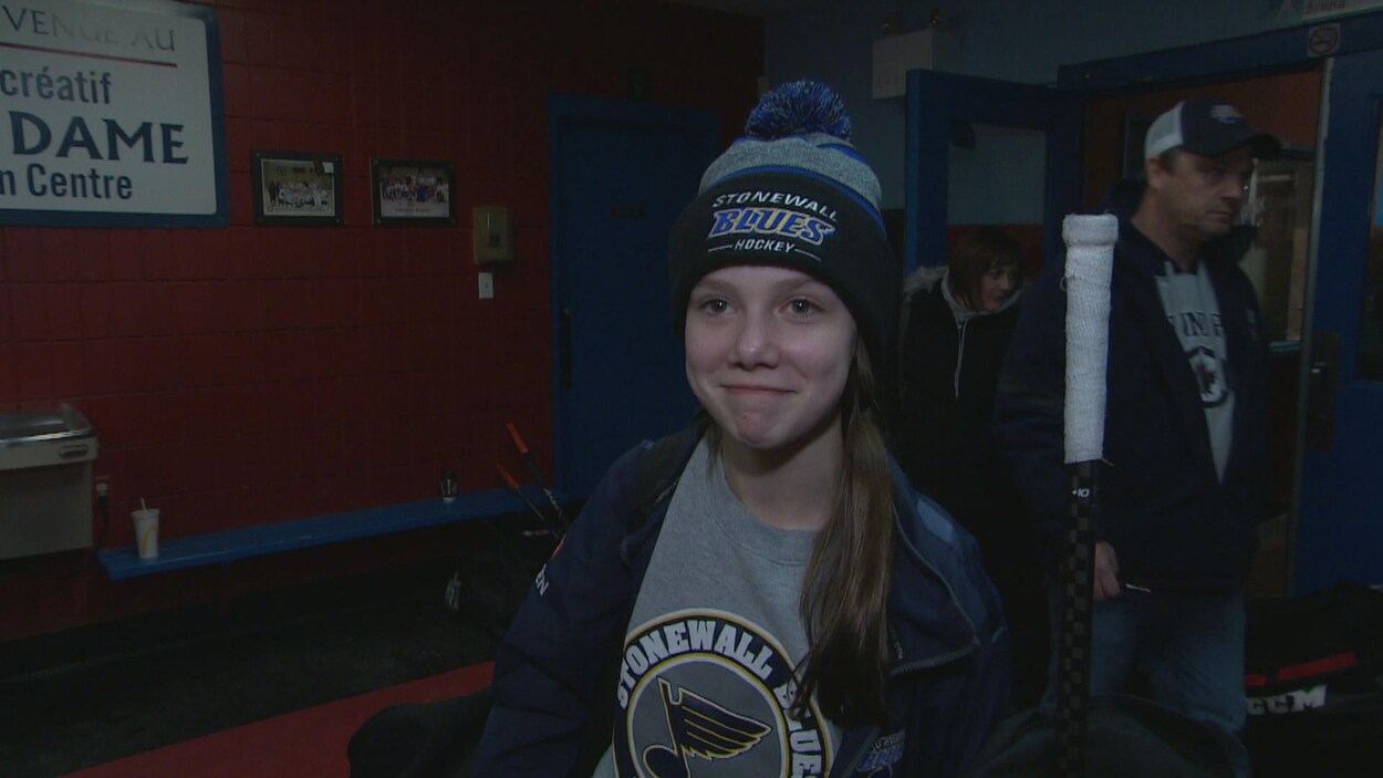 Une adolescente avec un bonnet de l'équipe de hockey des Blues de Stonewall.