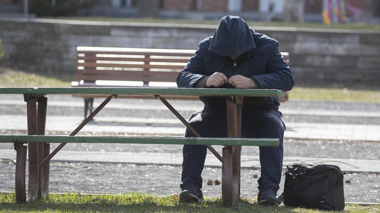 Un homme assis à une table de pique-nique dans un parc à Montréal.