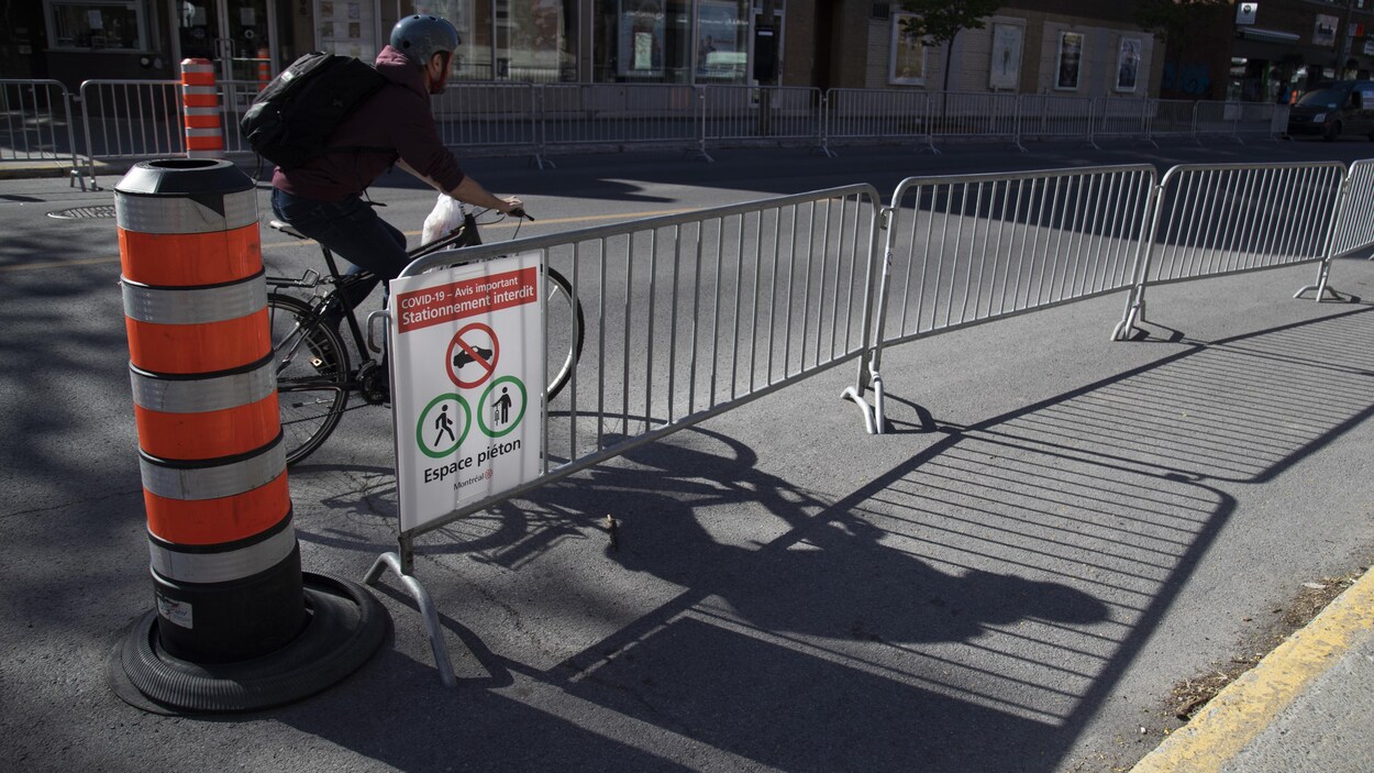 Un cycliste circule dans une rue de Montréal sur laquelle sont installées des clôtures.