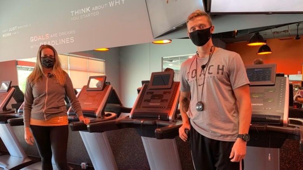 Un homme et une femme portant des masques debout dans une salle de sport.