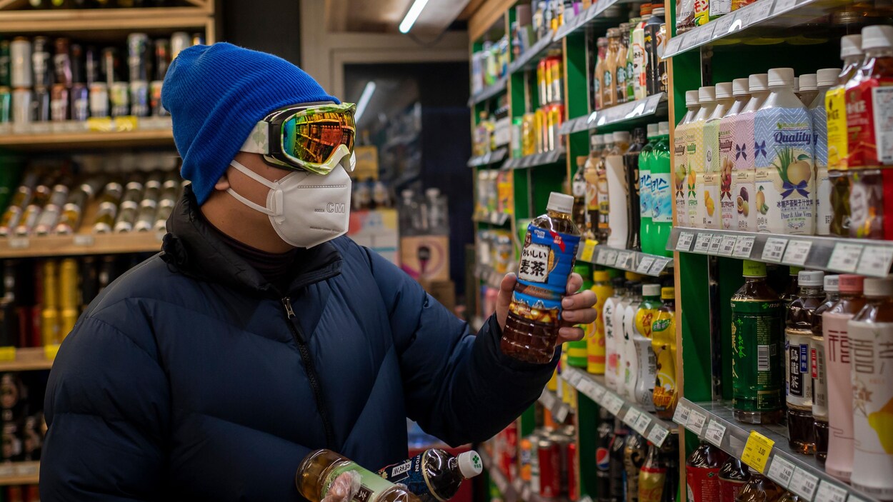 Un homme regarde une bouteille dans les allées muni de lunettes de ski et d'un masque.
