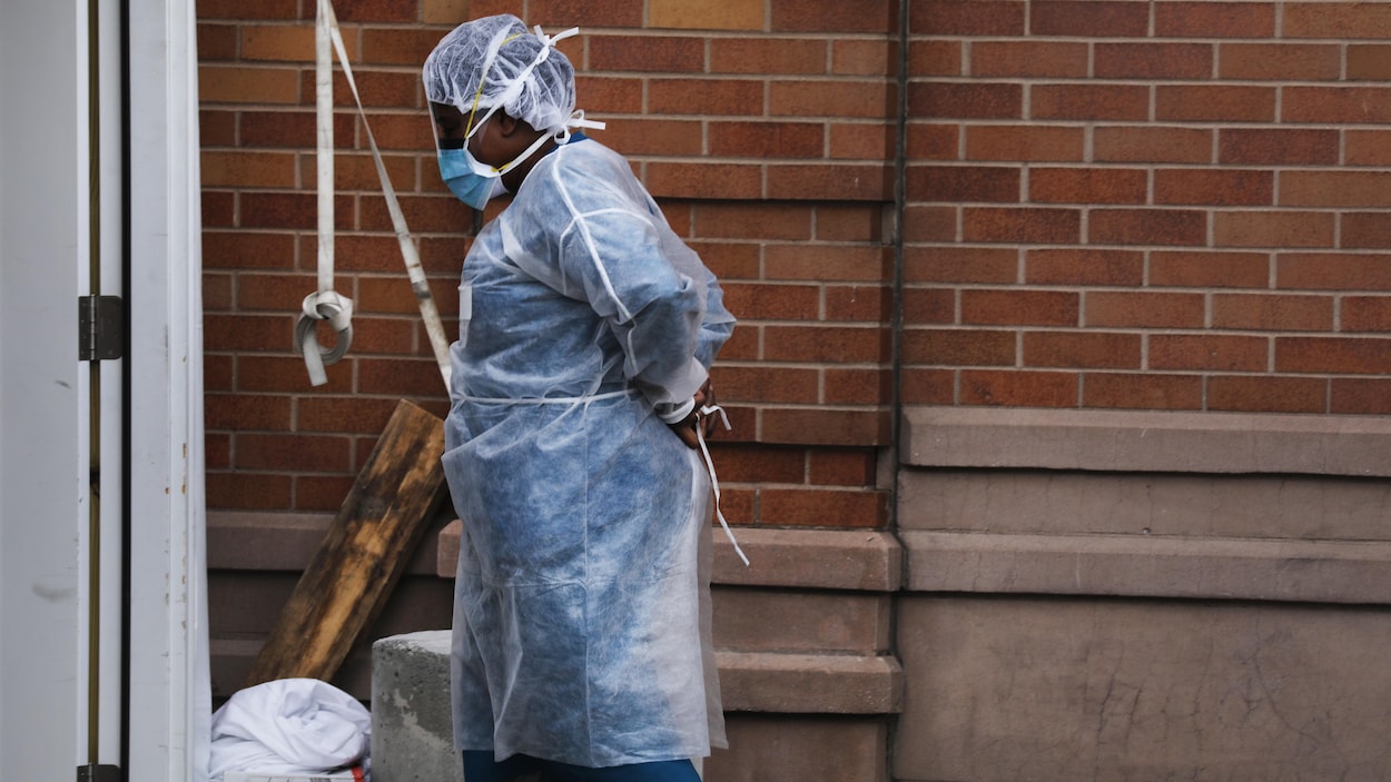 Une employée d'un hôpital de New York ajuste son équipement de protection avant de rentrer à l'intérieur.