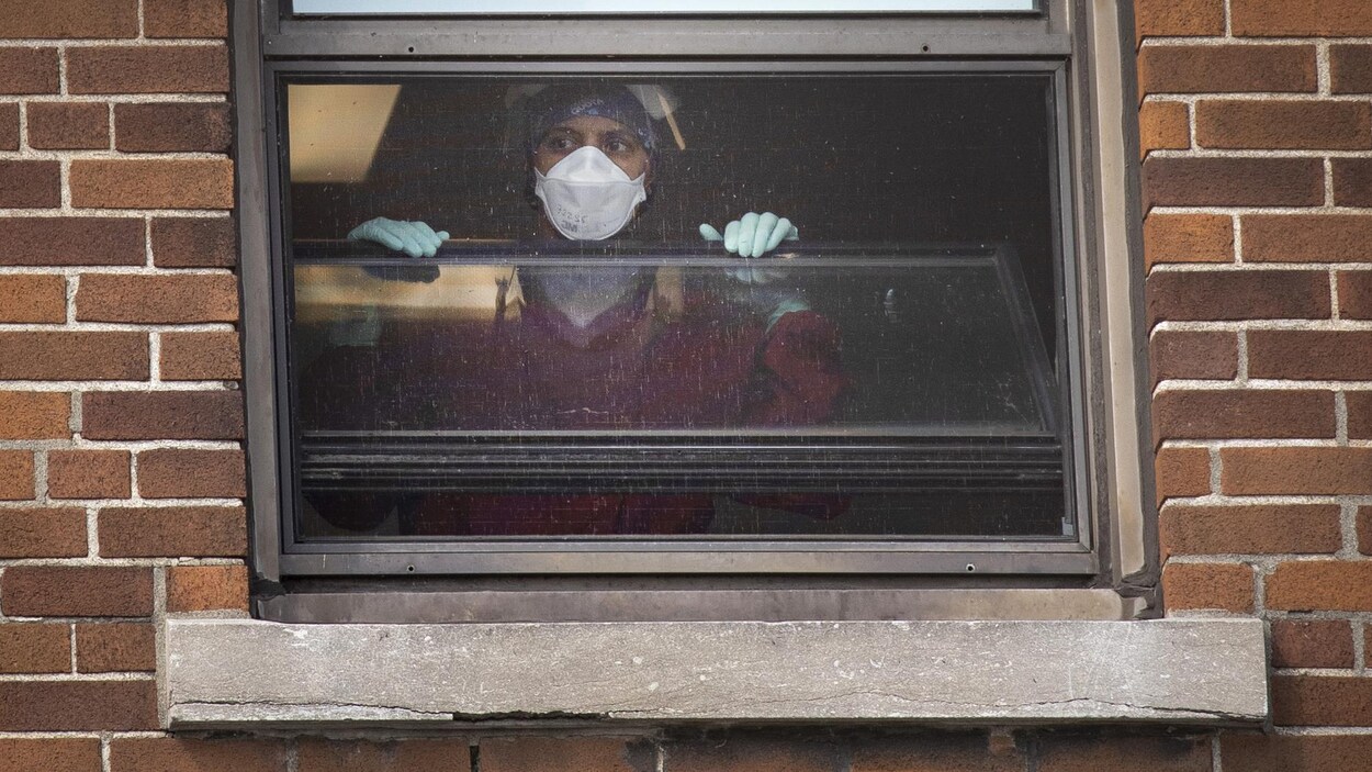 Une employée à la fenêtre d'un hôpital.