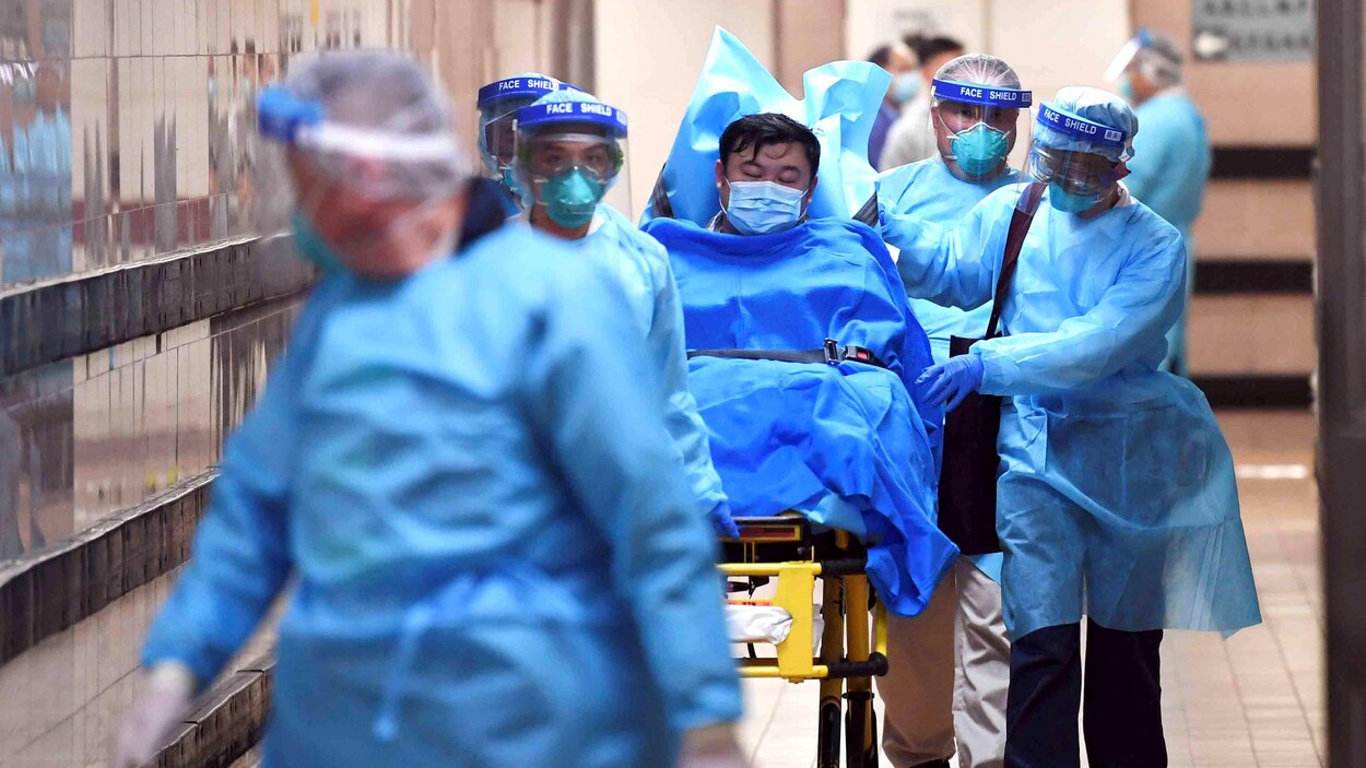 Des infirmiers en tenue de protection poussent une civière.