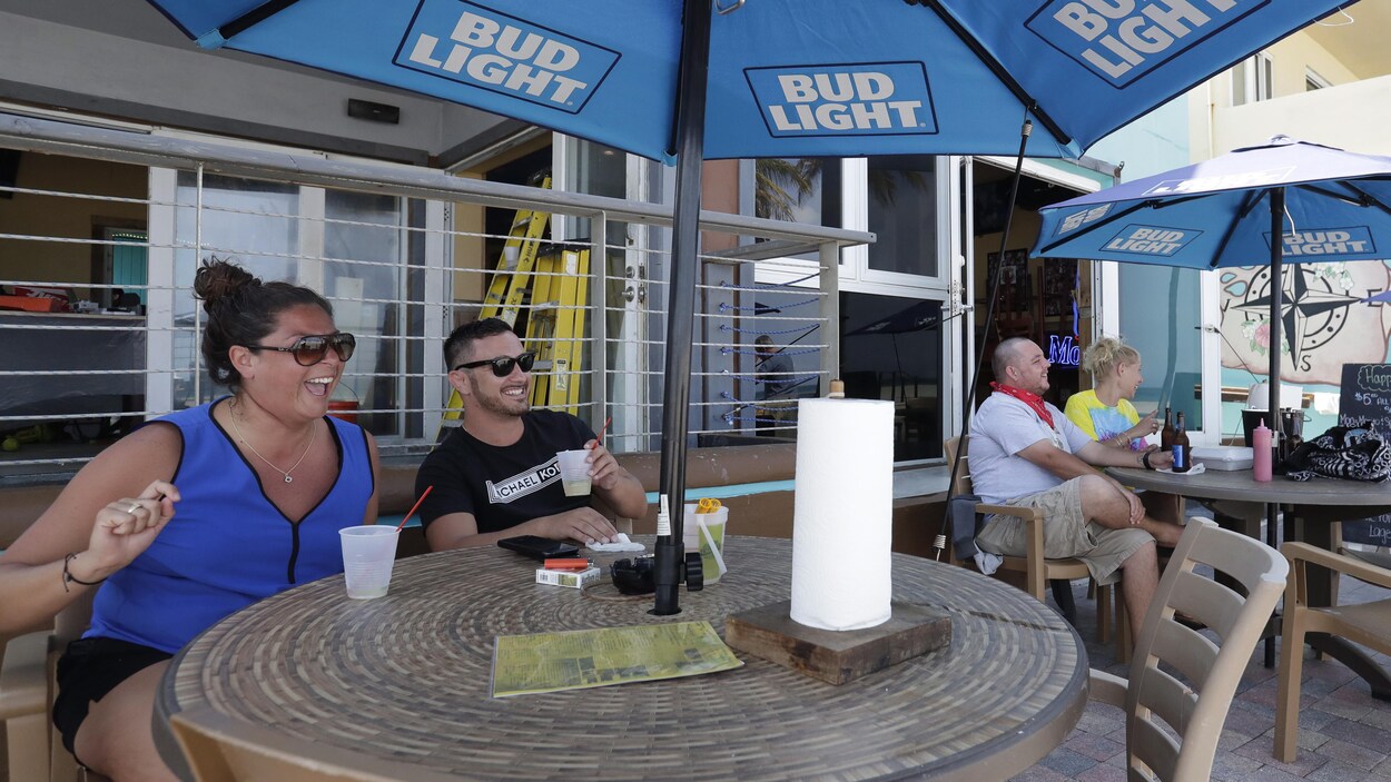 Un couple souriant prend des boissons sur une terrasse.