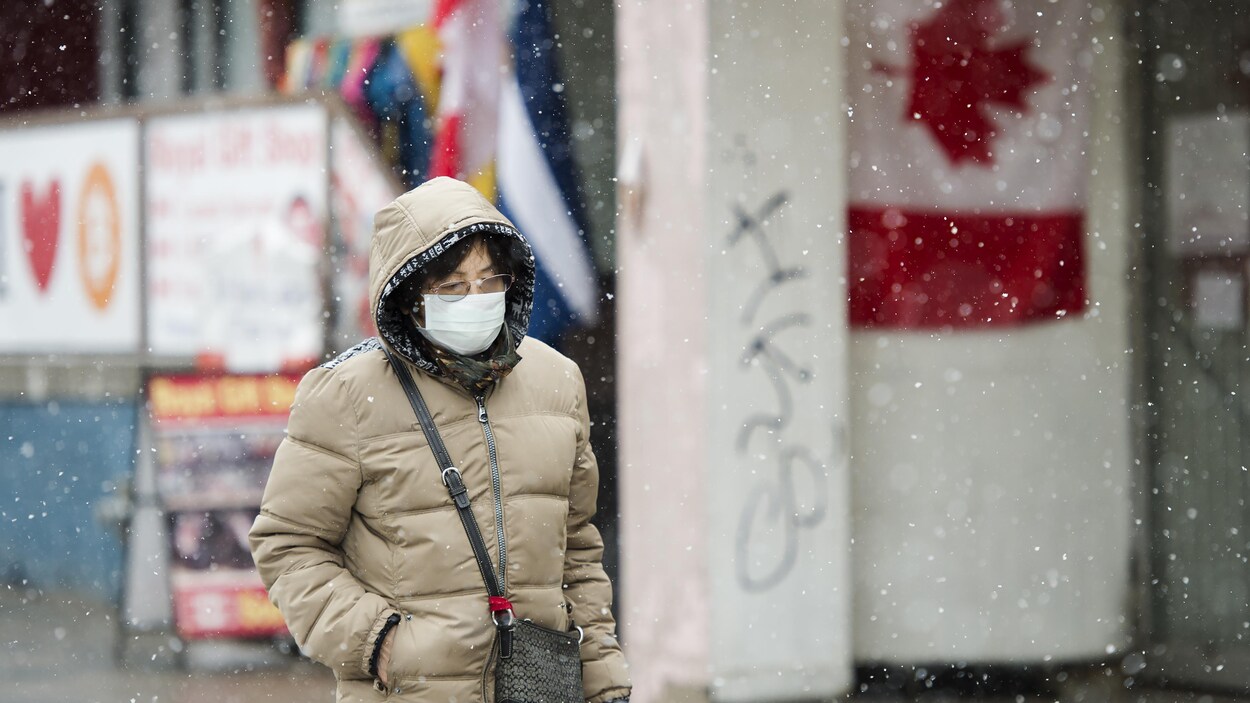 Une femme portant un masque marche dans la rue.