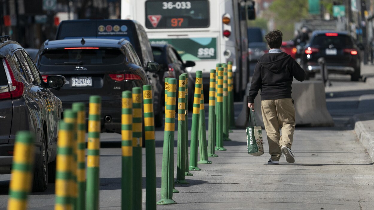 Un homme marche dans une voie réservée, séparée de la circulation par des piquets verts et jaunes.
