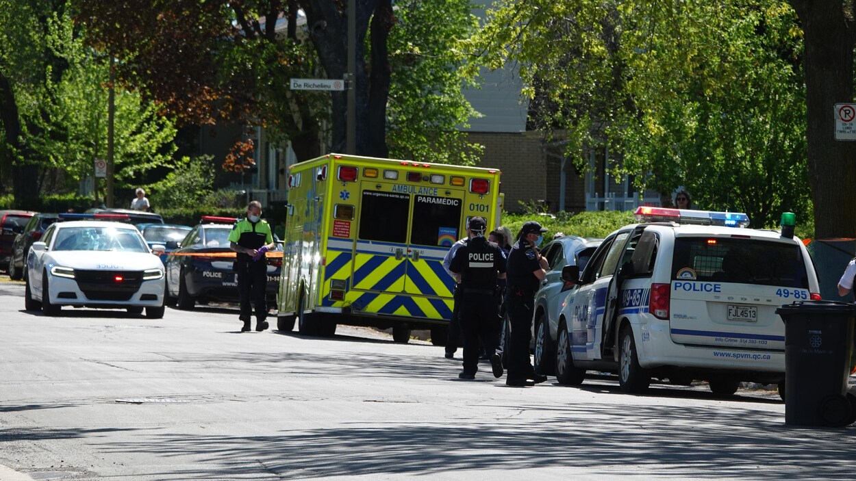 Des voitures de police et une ambulance dans une rue au périmètre sécurisé.