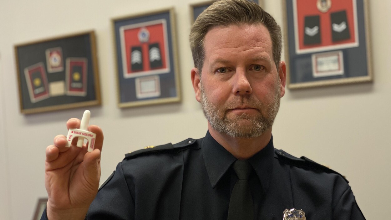 Un inspecteur de police tient un vaporisateur nasal de Narcan devant l'objectif.