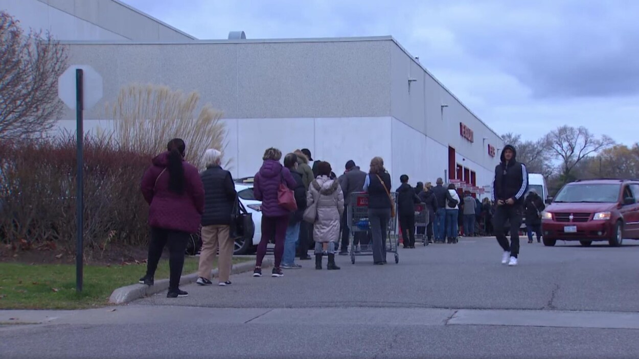 Des gens attendent pour entrer dans un magasin.