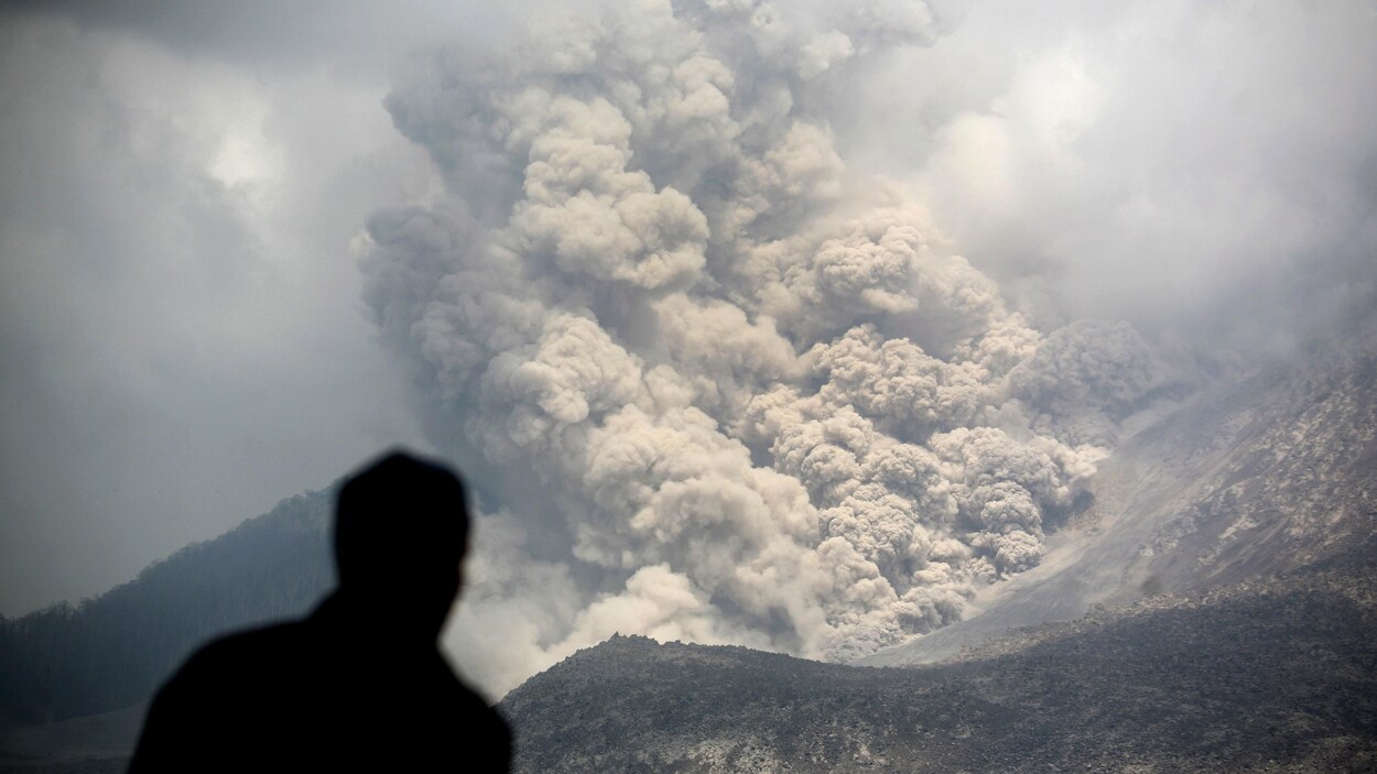 Un homme, de dos, observe une coulée pyroclastique.
