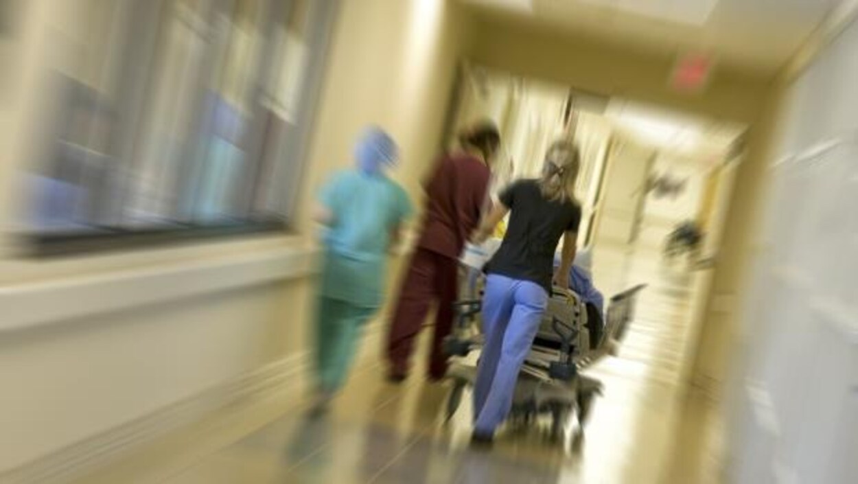 Des infirmières poussent une civière dans un couloir d'hôpital.