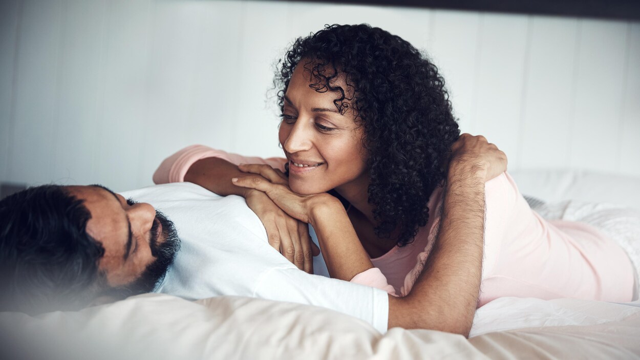 Un homme et une femme se regardent étendus sur un lit.