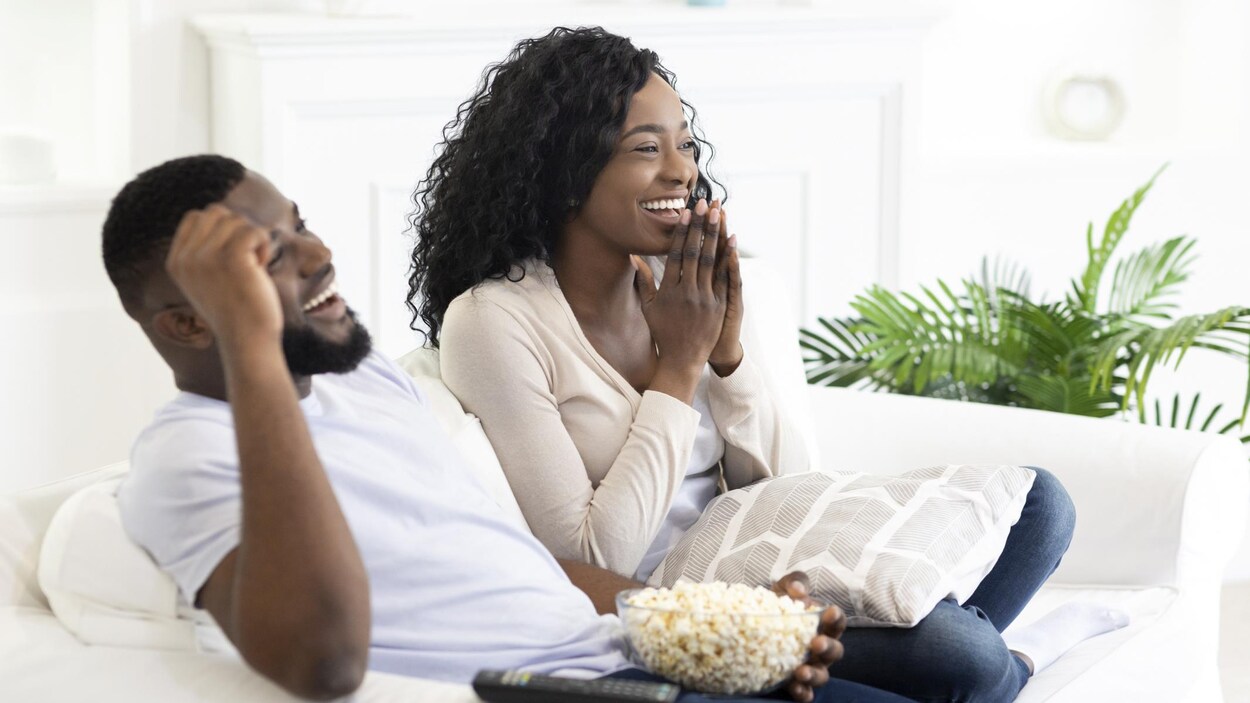 Un jeune couple regarde la télévision.