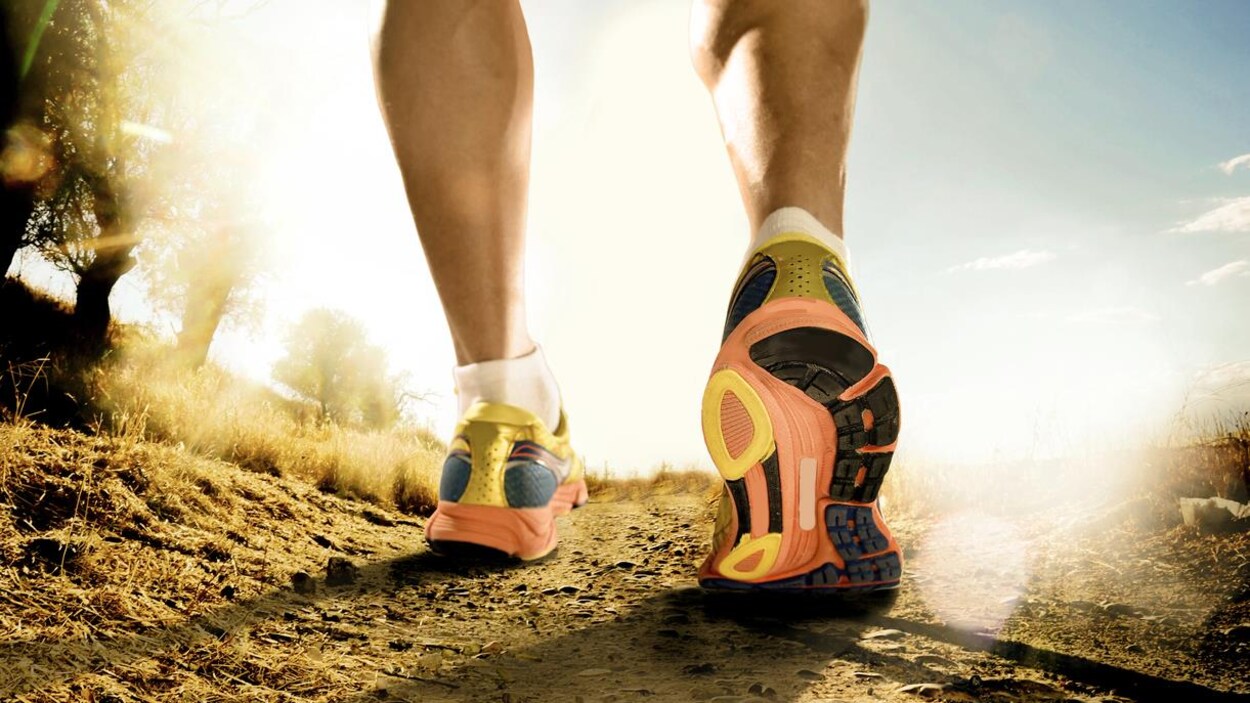 Un coureur gravit une pente dans un sentier.