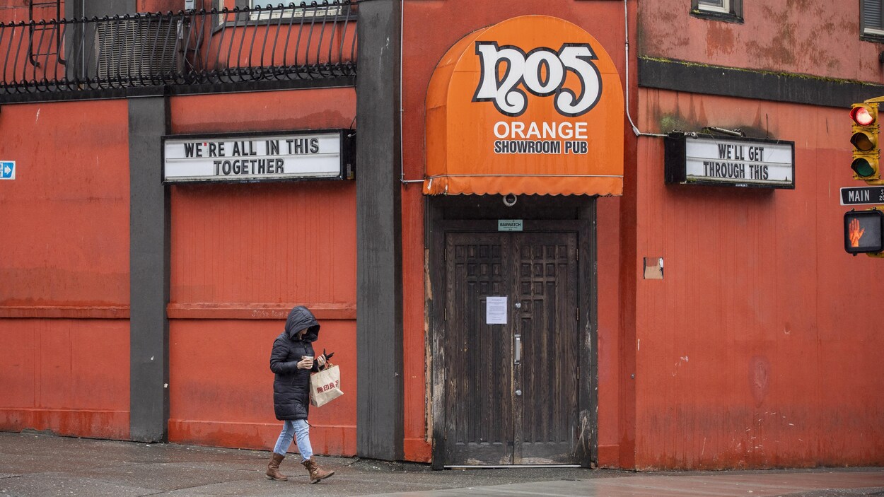 Une femme passe devant un bar d'effeuilleuses à Vancouver.