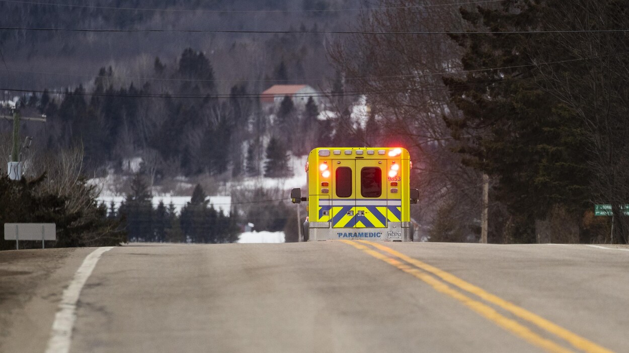 Une ambulance sur la route dans un décor champêtre et enneigé.