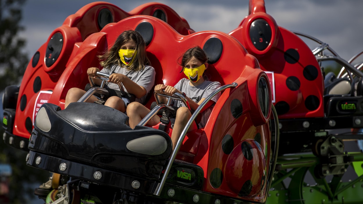 Deux jeunes filles portent un masque jaune dans un manège au parc d'amusement Playland à Vancouver.