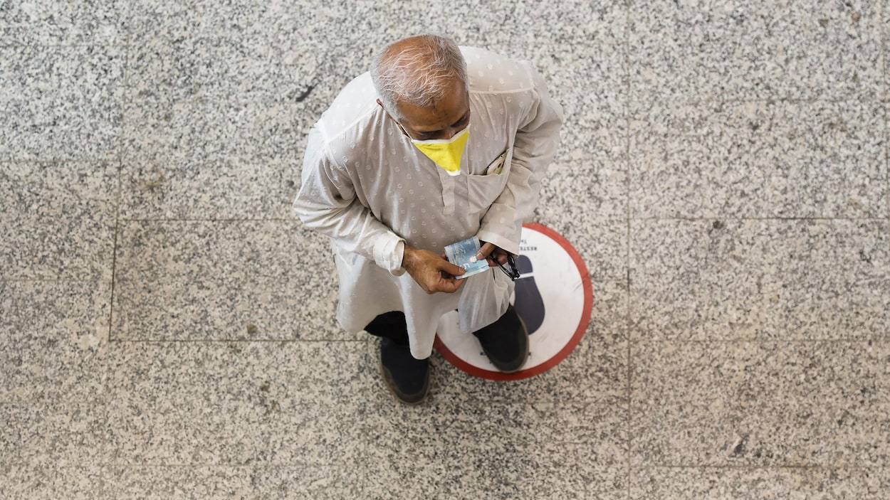 Un homme porte un masque et pratique la distanciation physique à l'aéroport Pearson.