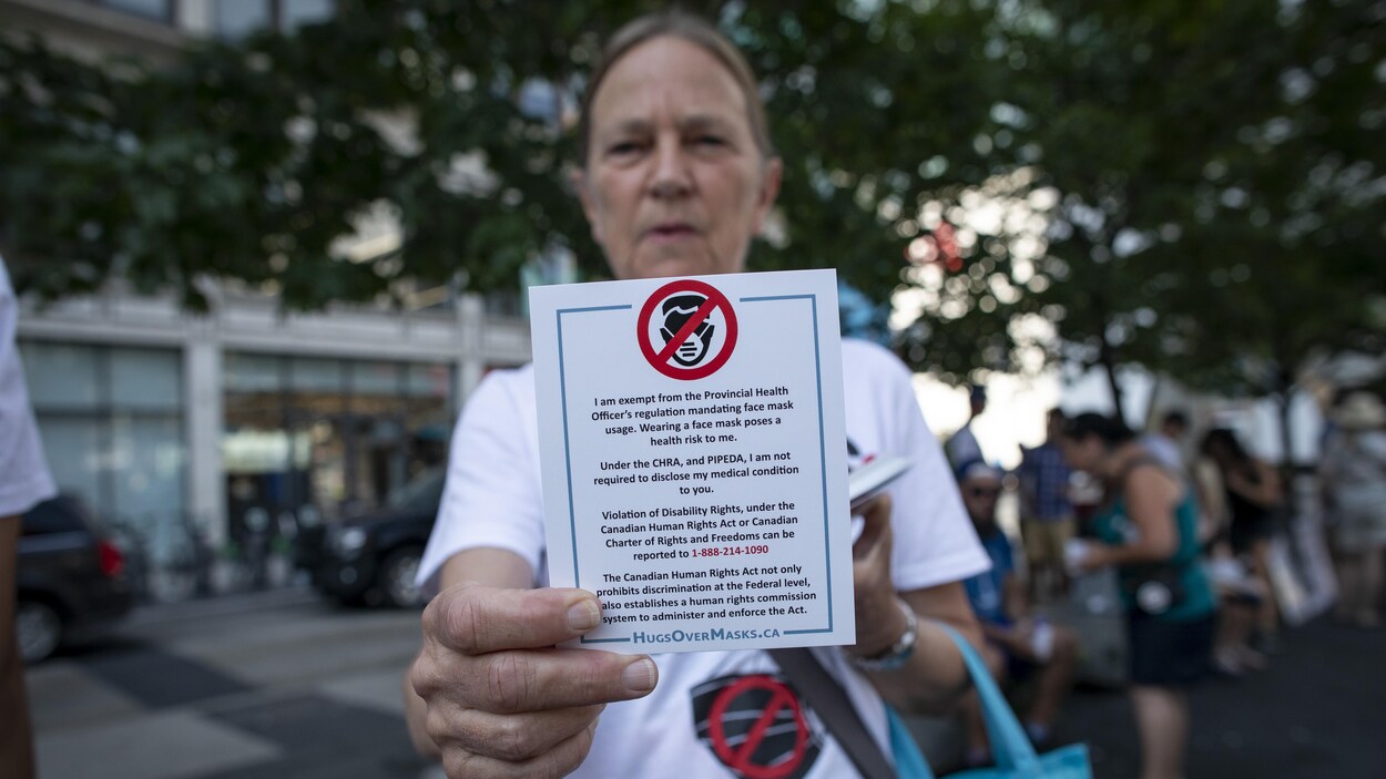 Une manifestante qui s'oppose au port du masque obligatoire à Toronto brandit une carte.