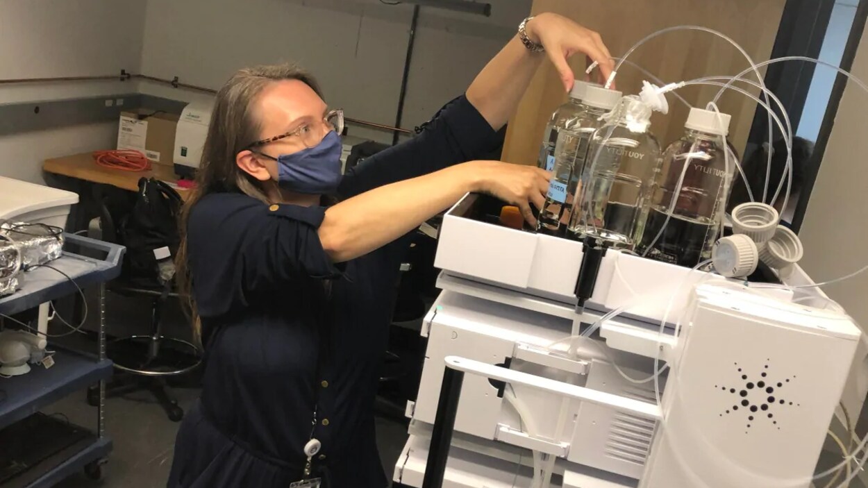 Une femme masquée ajuste des échantillons liquides.