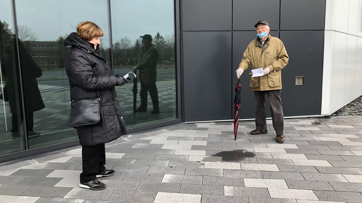 Monique Champagne et Laurent Lessard, à l'extérieur, se tiennent à bonne distance.