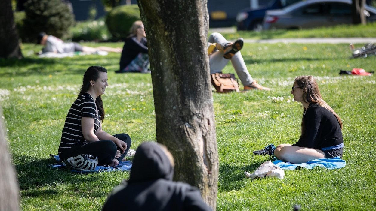 Des personnes assises dans l'herbe dans un parc.
