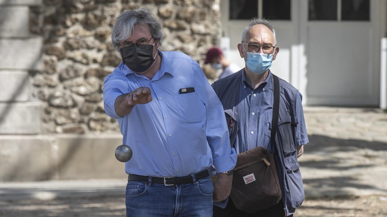 Deux personnes portant un masque et jouant à la pétanque.