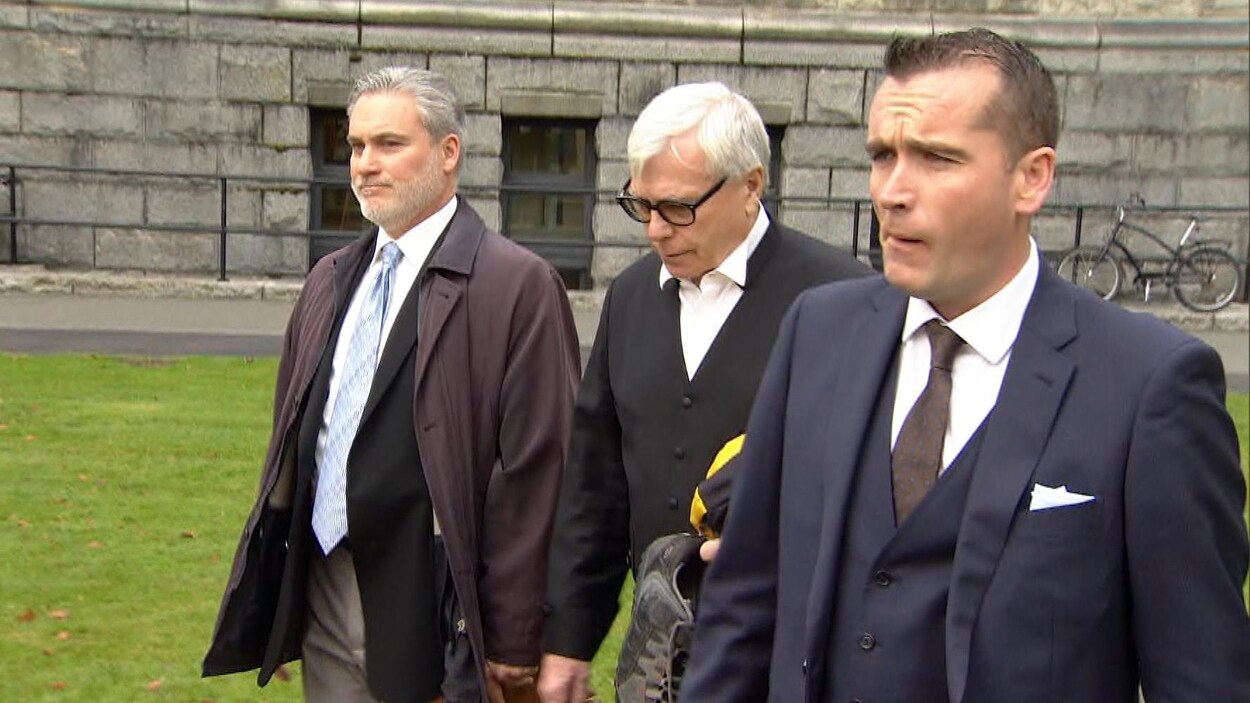 Trois hommes marchent côte à côte.