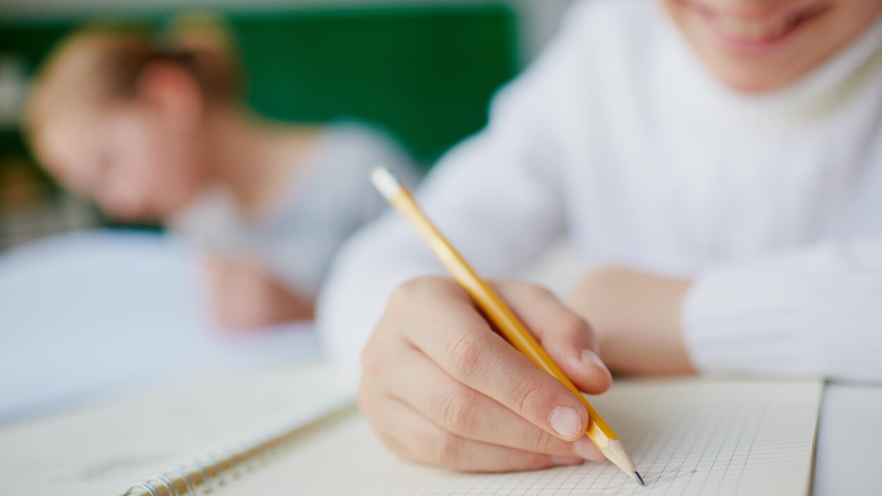 Image d'un élève en classe utilisant un crayon de bois.