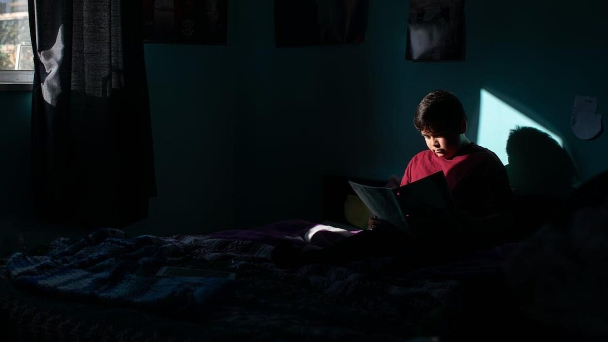 Creighton Angus-Morrison lit des notes dans la pénombre.