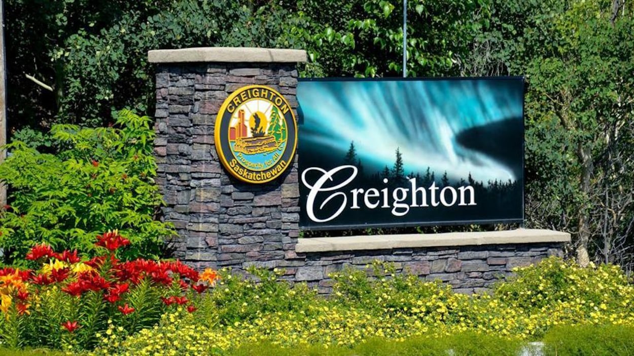 Un mur de briques au milieu d'un jardin où est indiqué la Ville de Creighton.
