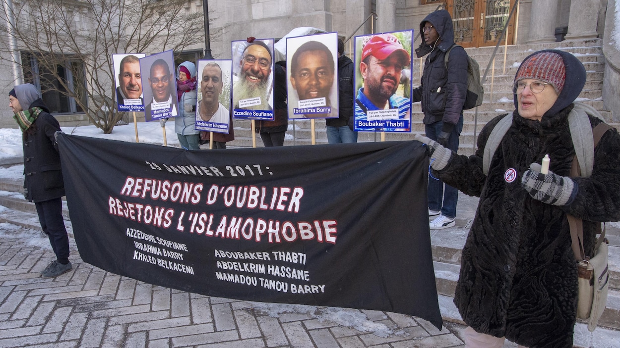 Des gens tiennent une banderole et des affiches.
