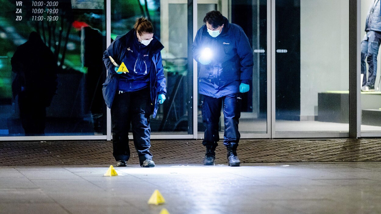 Deux spécialistes de la police scientifique, lampes à la main, tentent de trouver des indices sur la scène de l'agression.