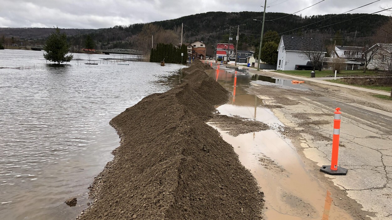De la terre empilée pour bloquer de l'eau près d'une route.